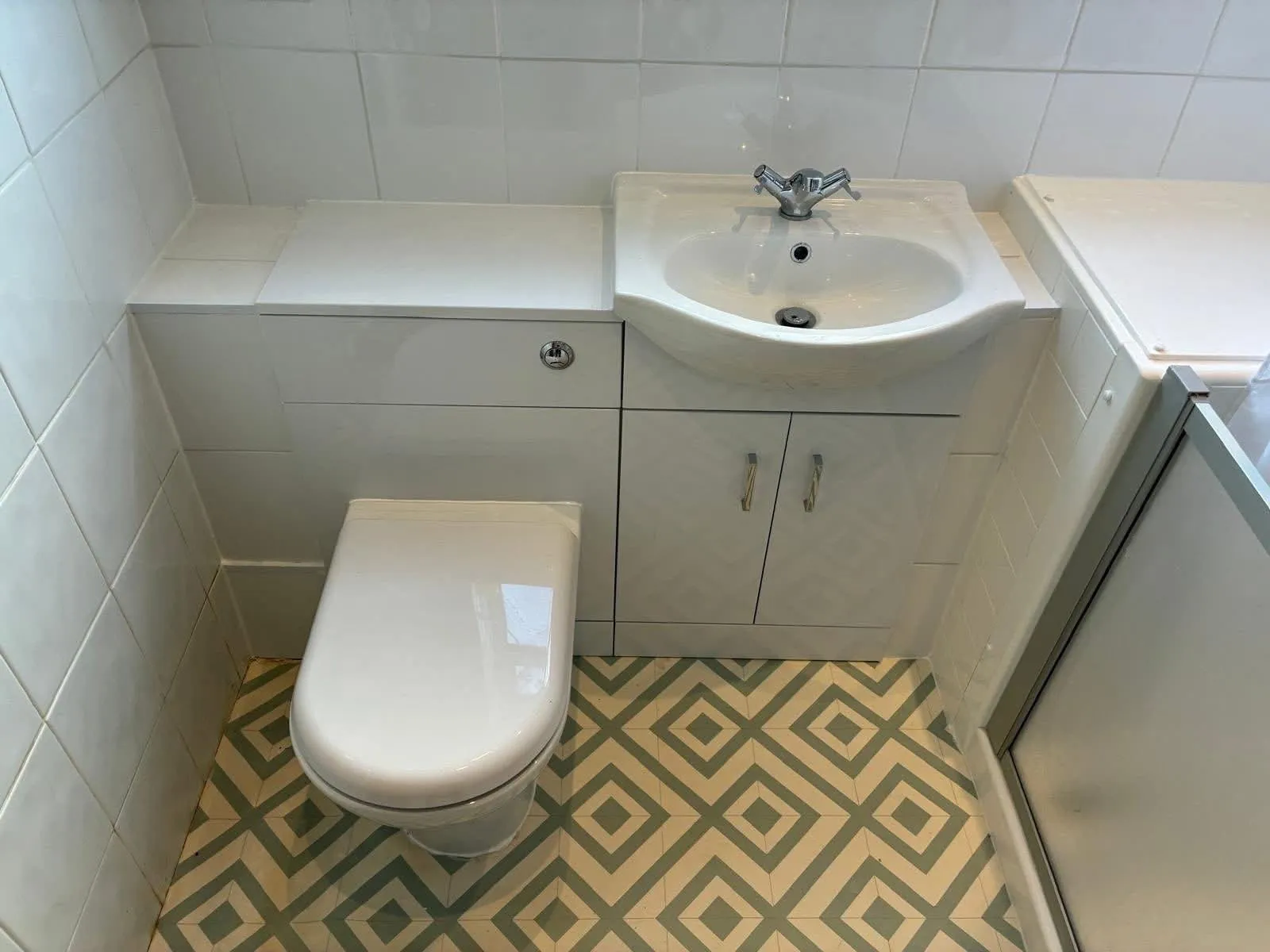 White toilet and basin vanity unit fitted in a tiled bathroom