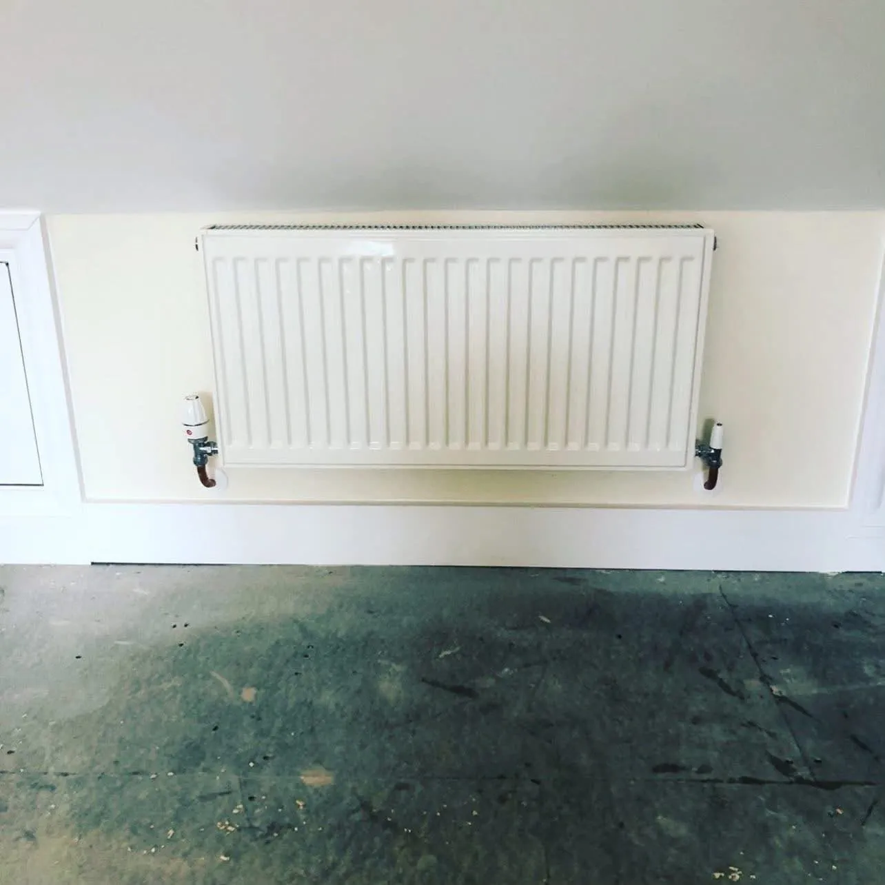 New radiator with thermostatic valve fitted under a sloped ceiling