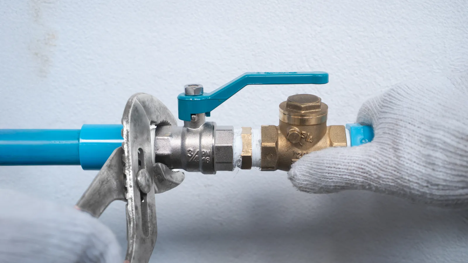 Plumber fitting an isolation valve and brass check valve to a water pipe