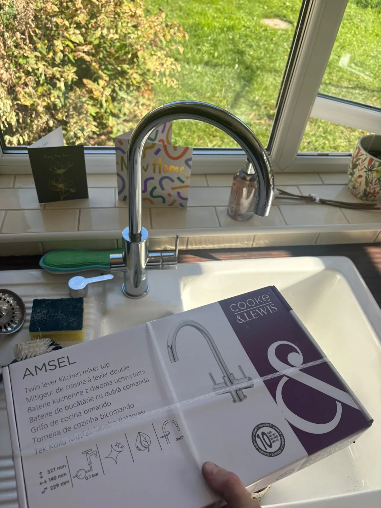 New chrome twin-lever kitchen mixer tap fitted on a kitchen sink