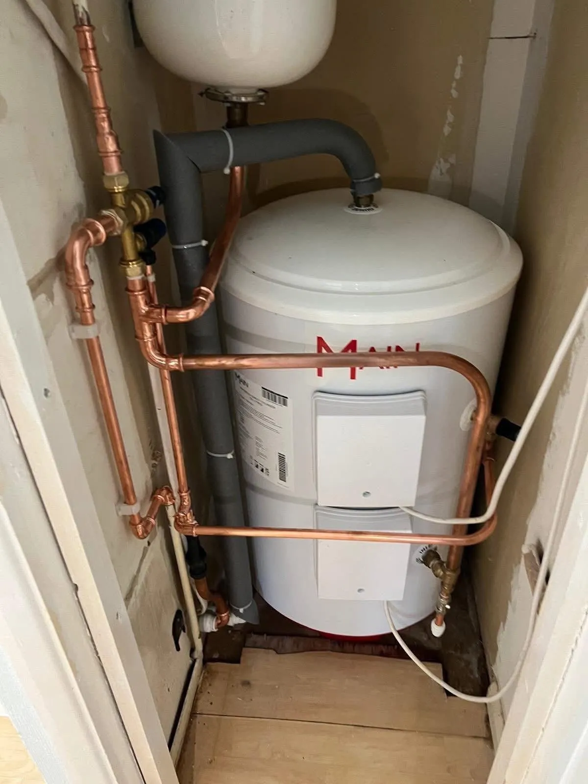 New copper pipework around a hot water cylinder in an airing cupboard