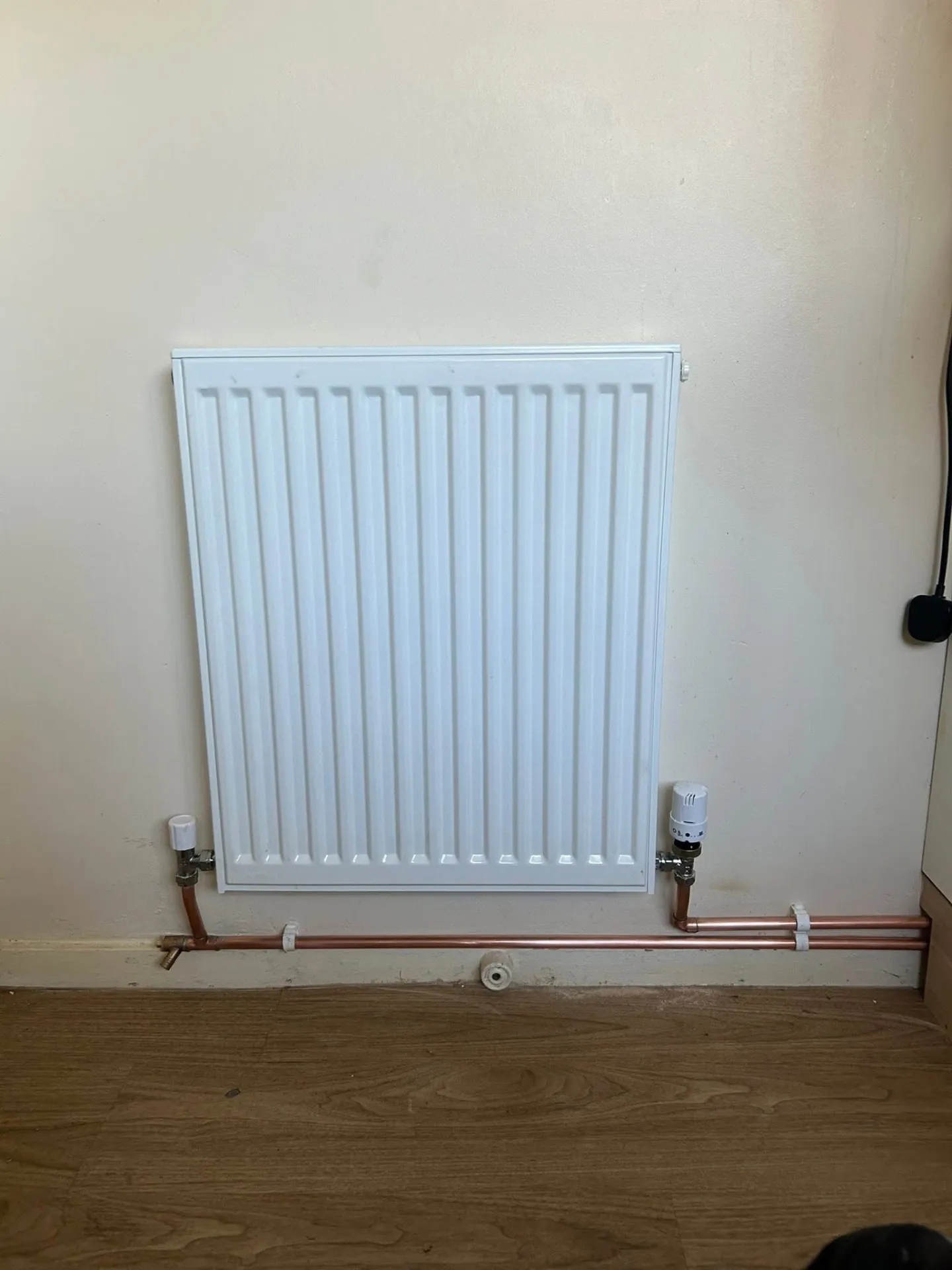 Single-panel radiator installed with new copper pipework and thermostatic valve